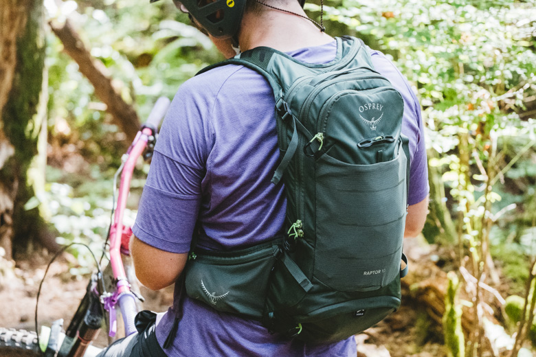 A man wearing a green mountain bike backpack in a forest B