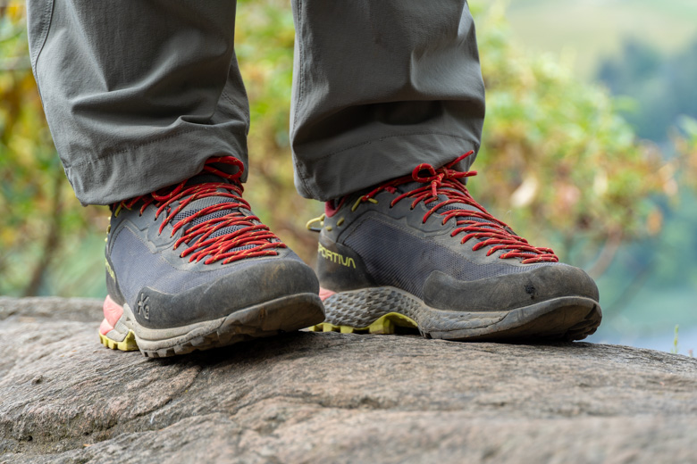 A pair of grey and red approach shoes on a rock