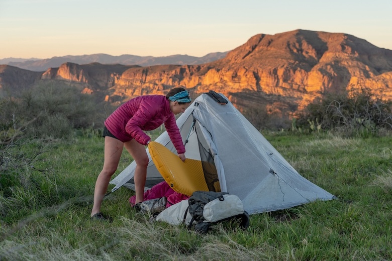 A woman sets up an ultralight sleeping pad in her tent while camping in the Superstitions