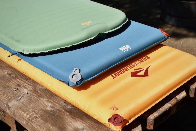 A stack of camping mattresses laid out in the sun