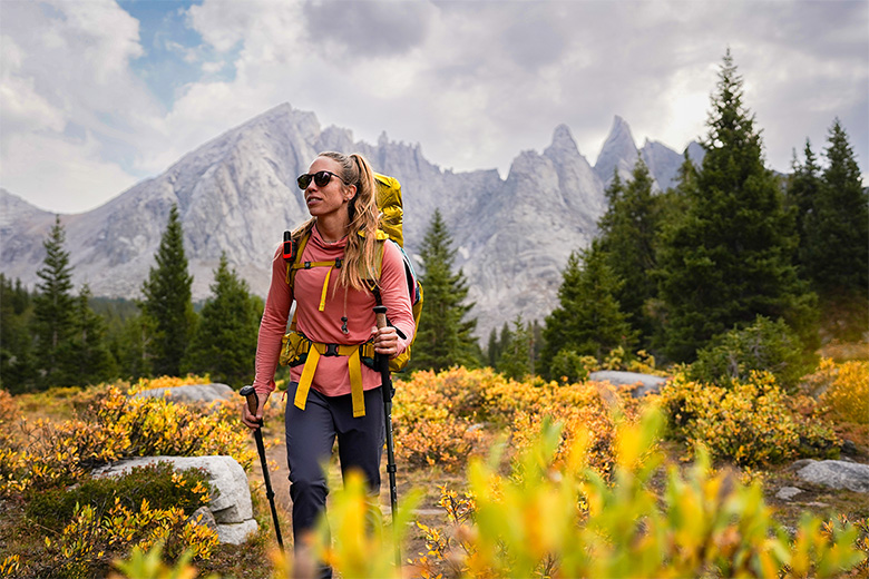 A woman hiking in a field full of autumn colors while wearing a lightweight hoodie.