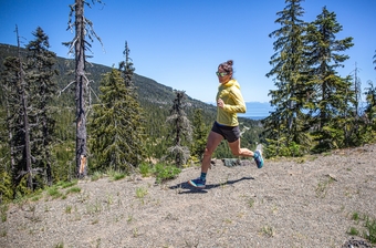 A woman running down a trail wearing the Hoka Speedgoat 6 shoe