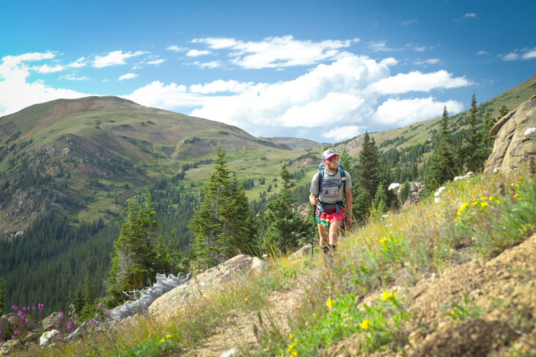 The author hiking on the CDT in Colorado, with a blue ski and mountains in the background