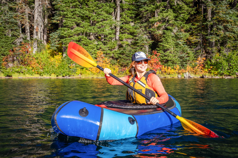 A woman paddles the Alpacka Refuge packraft on a lake in Washington.