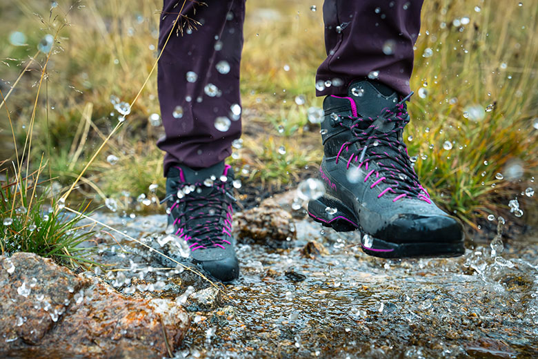 A hiker splashes through a puddle in their favorite hiking boots.