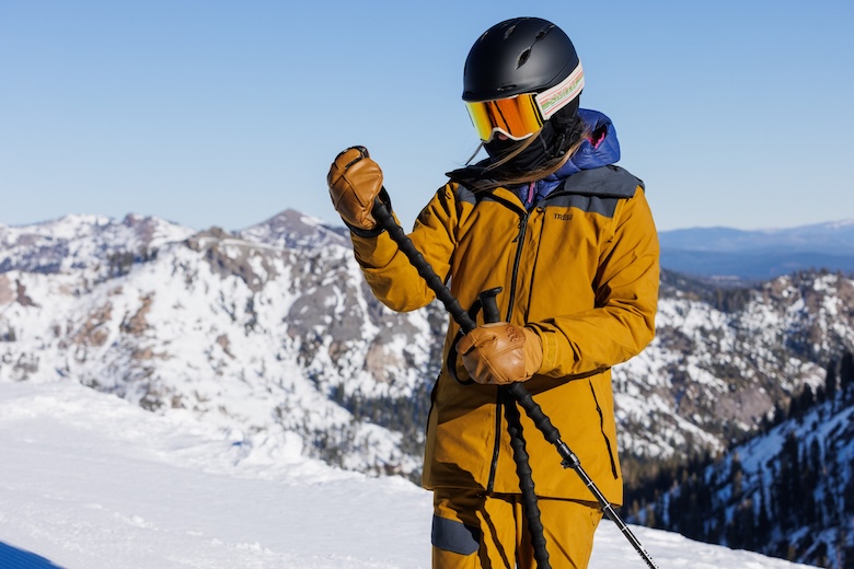 A suited up skier assesses one of their ski poles