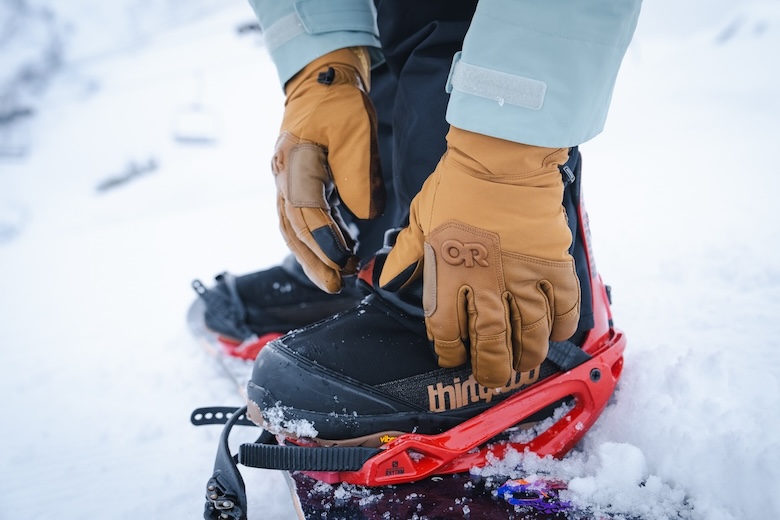 Close up photo of a person strapping into a snowboard binding