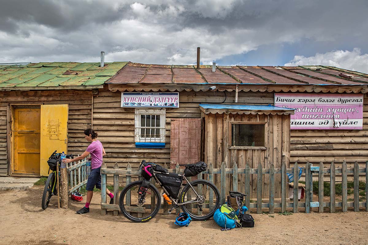 A woman on a bikepacking trip in Mongolia stops at a store in the mountains