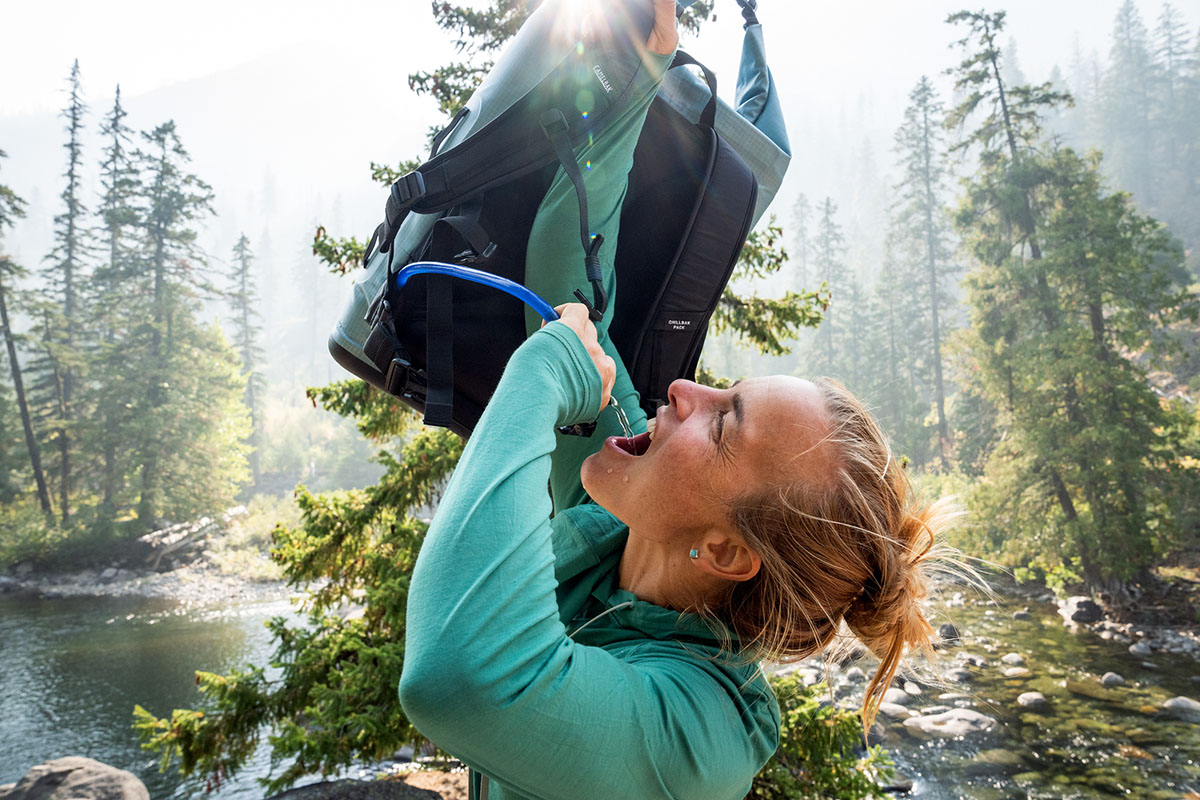 A hiker drinks from the bladder attachment on her backpack cooler.