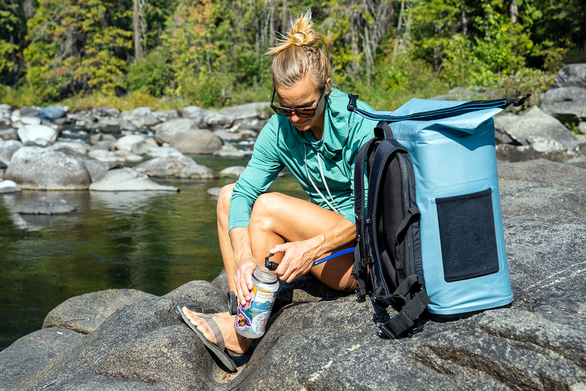 A woman fills her Nalgene bottle with the bladder from her Camelbak backpack cooler.