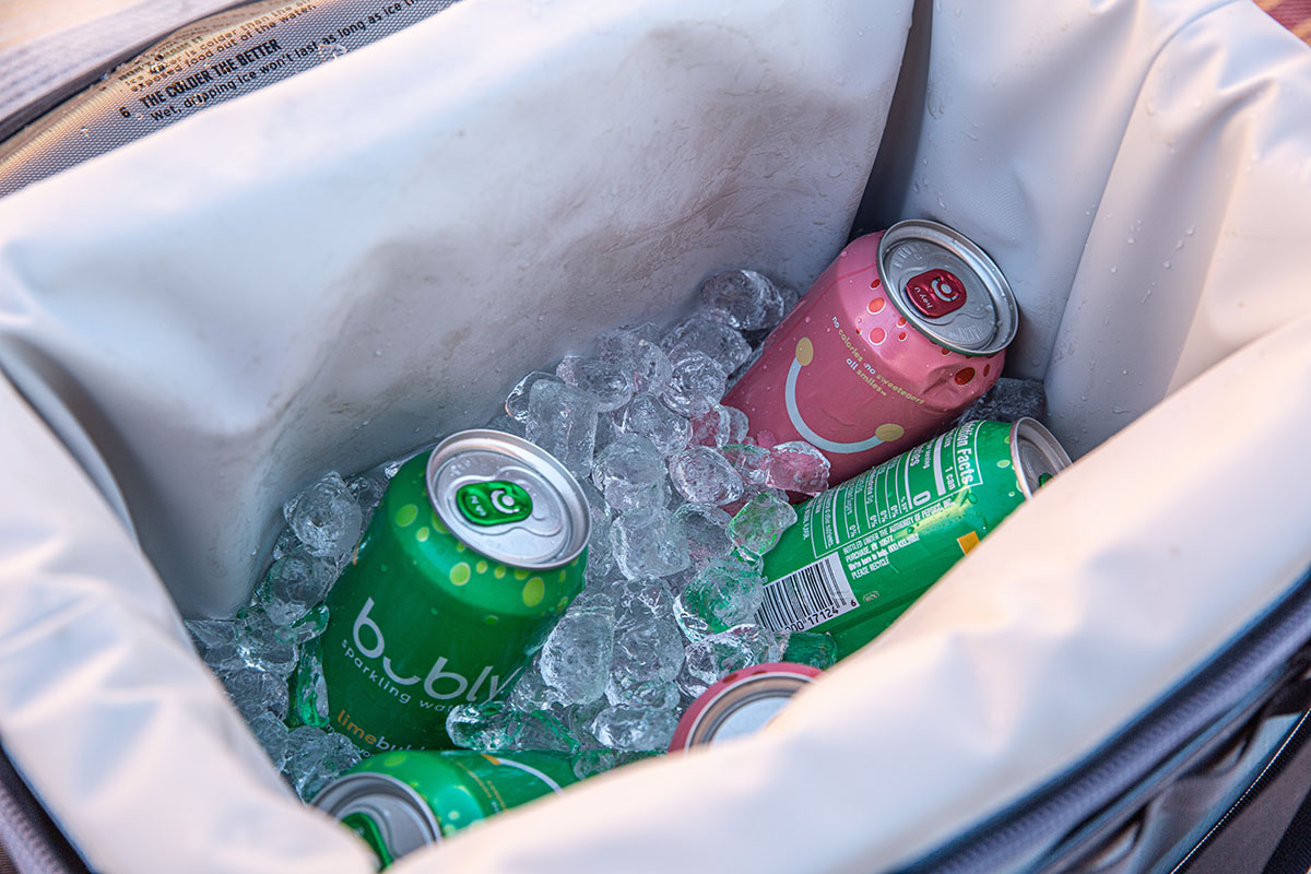 A close up view of the interior liner on a backpack cooler, filled with ice and bubbly water.
