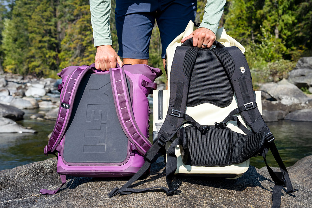 A hiker holds up two backpack coolers, illustrating the difference in size. 