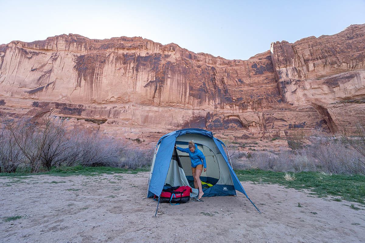 A camper pitches a tent in a canyon of steep red rock.