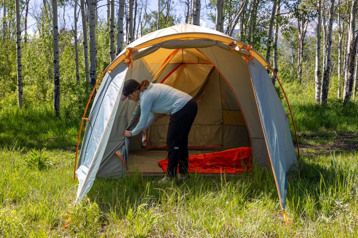 A woman adjusts the door on her camping tent.