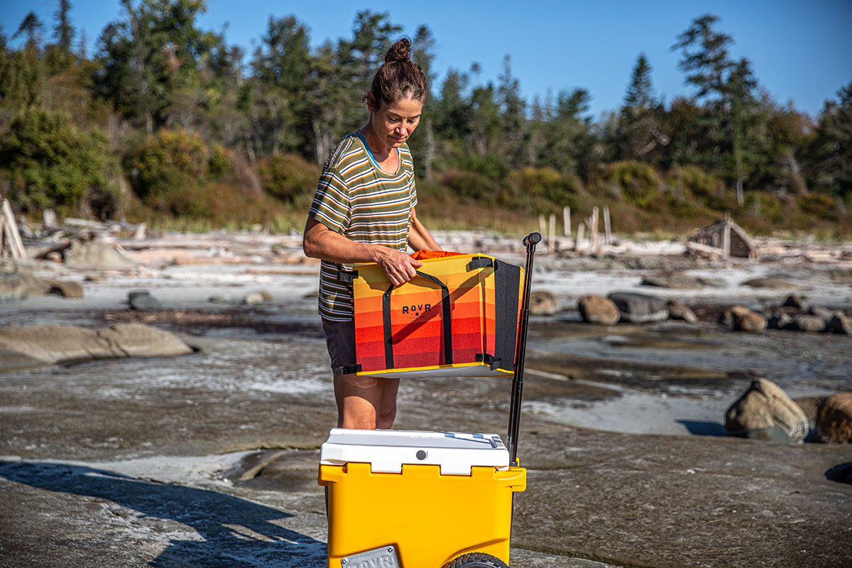 A woman stacks a custom storage bin on top of her Rovr cooler.