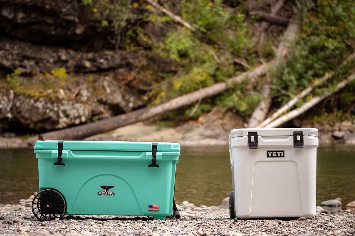 An Orca cooler and Yeti cooler sit side-by-side on the ground.