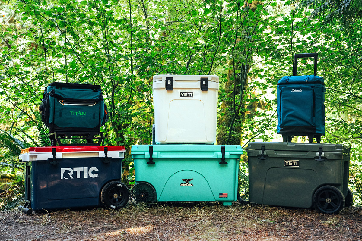 A group of wheeled coolers are stacked at a campsite for testing.
