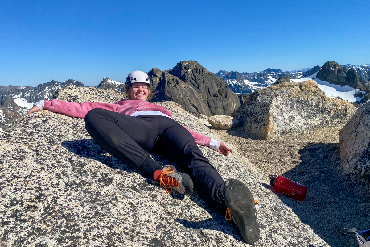 A woman lying on a rock slab while looking at climbing shoes_0