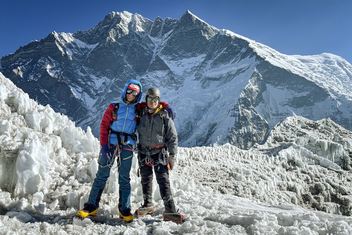 Two climbers pose for a photo on a mountain peak.