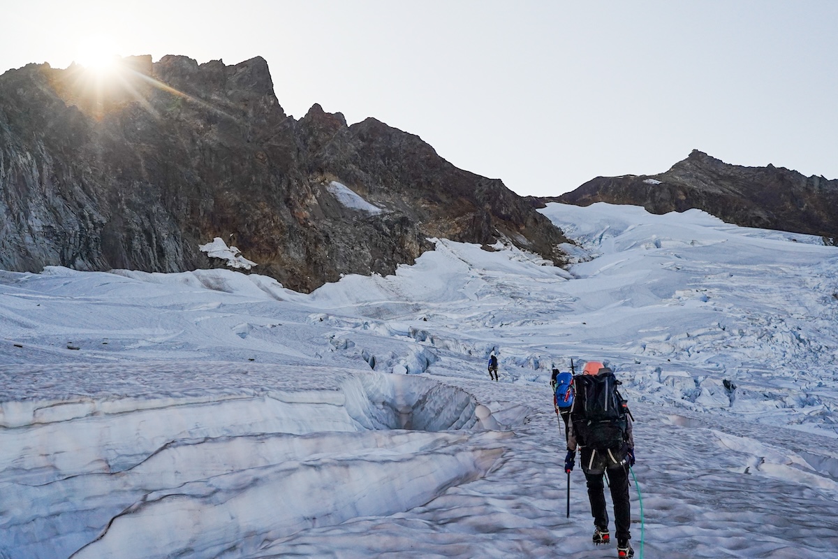 A group takes a glacier hike across the snow. 