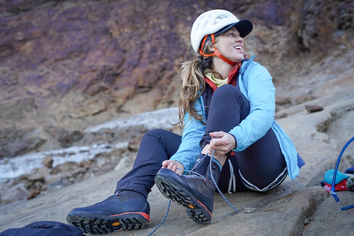 A woman laces her boots before a technical climb.