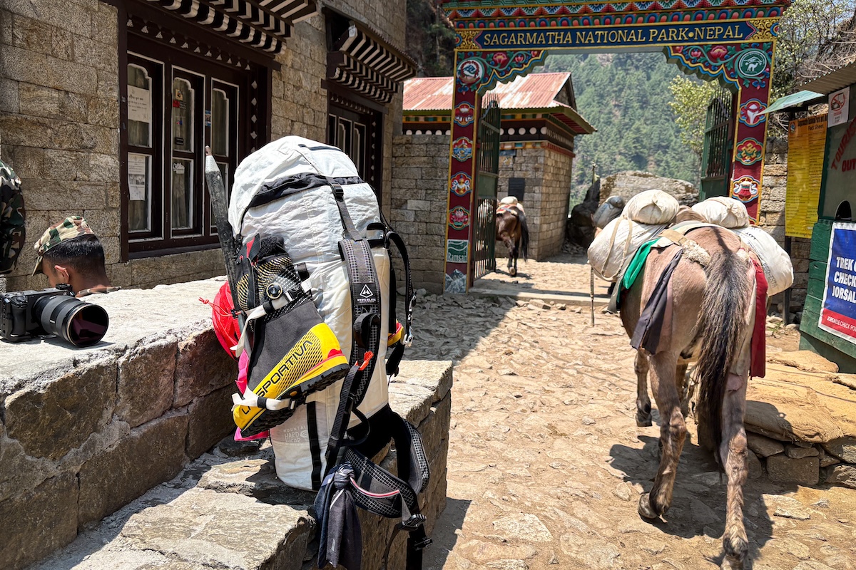 A donkey is loaded with supplies and a backpack sits at the ready in the Himalaya