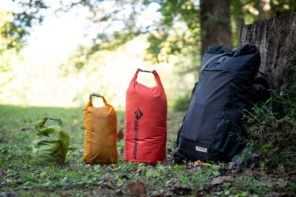 Dry bags lined up near a backpack
