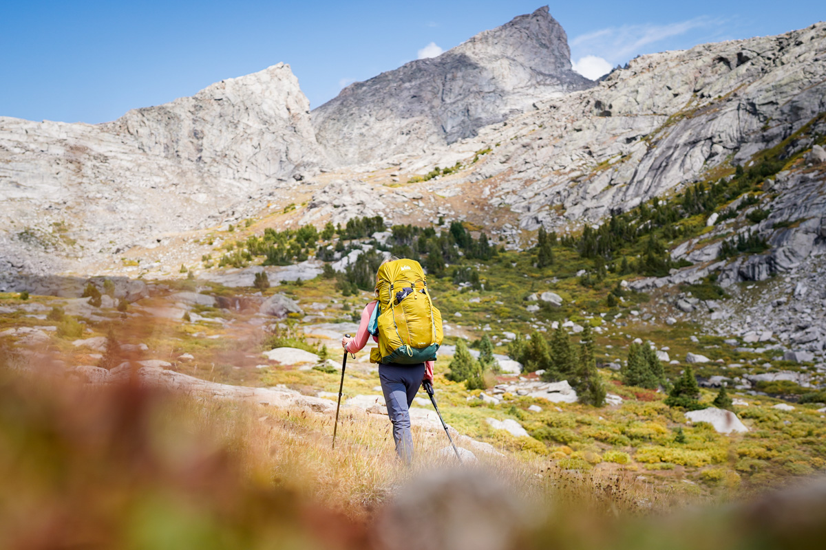 A woman backpacking with mountains in the background