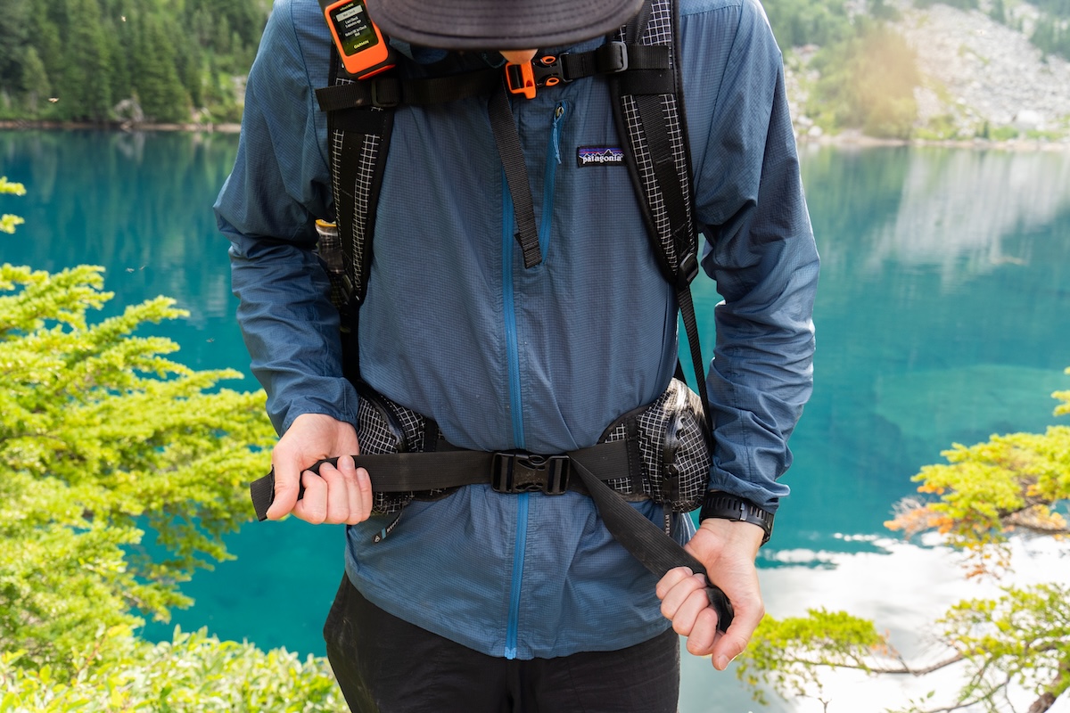 A man tightens the waist straps of a backpack