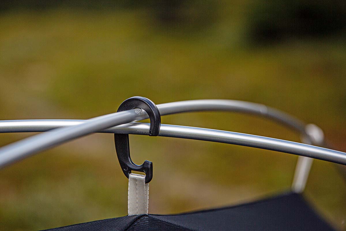 A black hook connecting a budget backpacking tent to tent poles