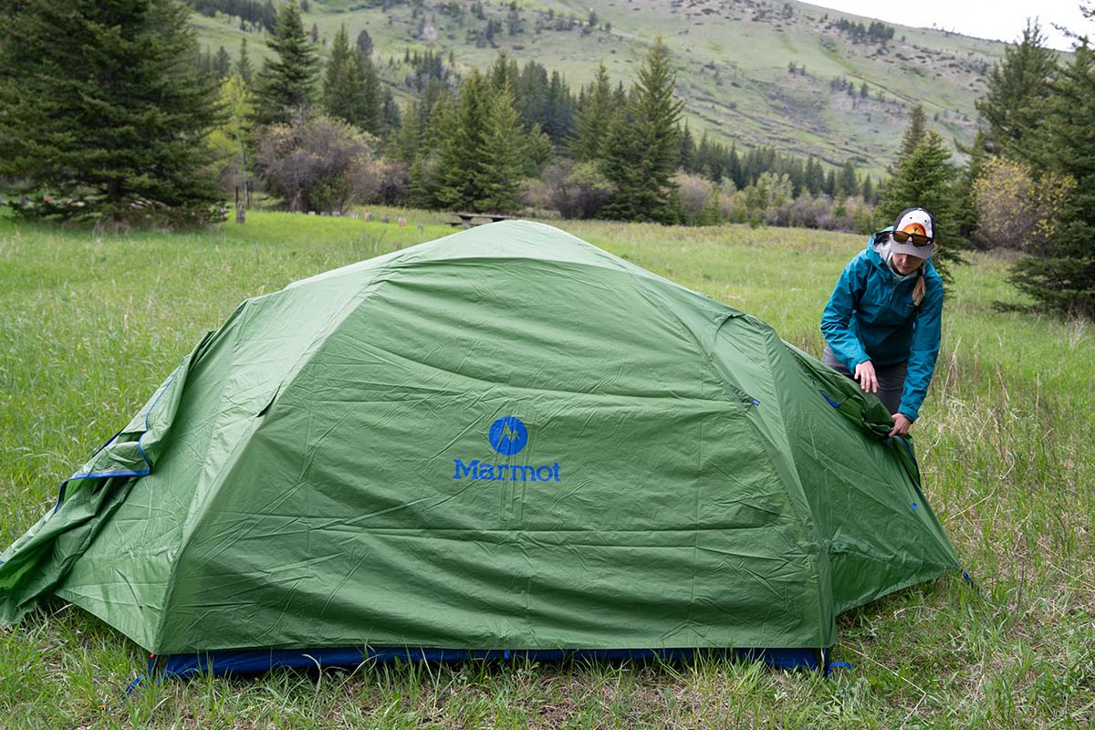 A woman setting up a green budget backpacking tent