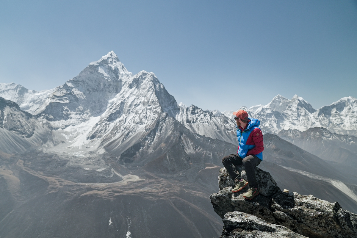 A man sits on a ridge while backpacking in Nepal
