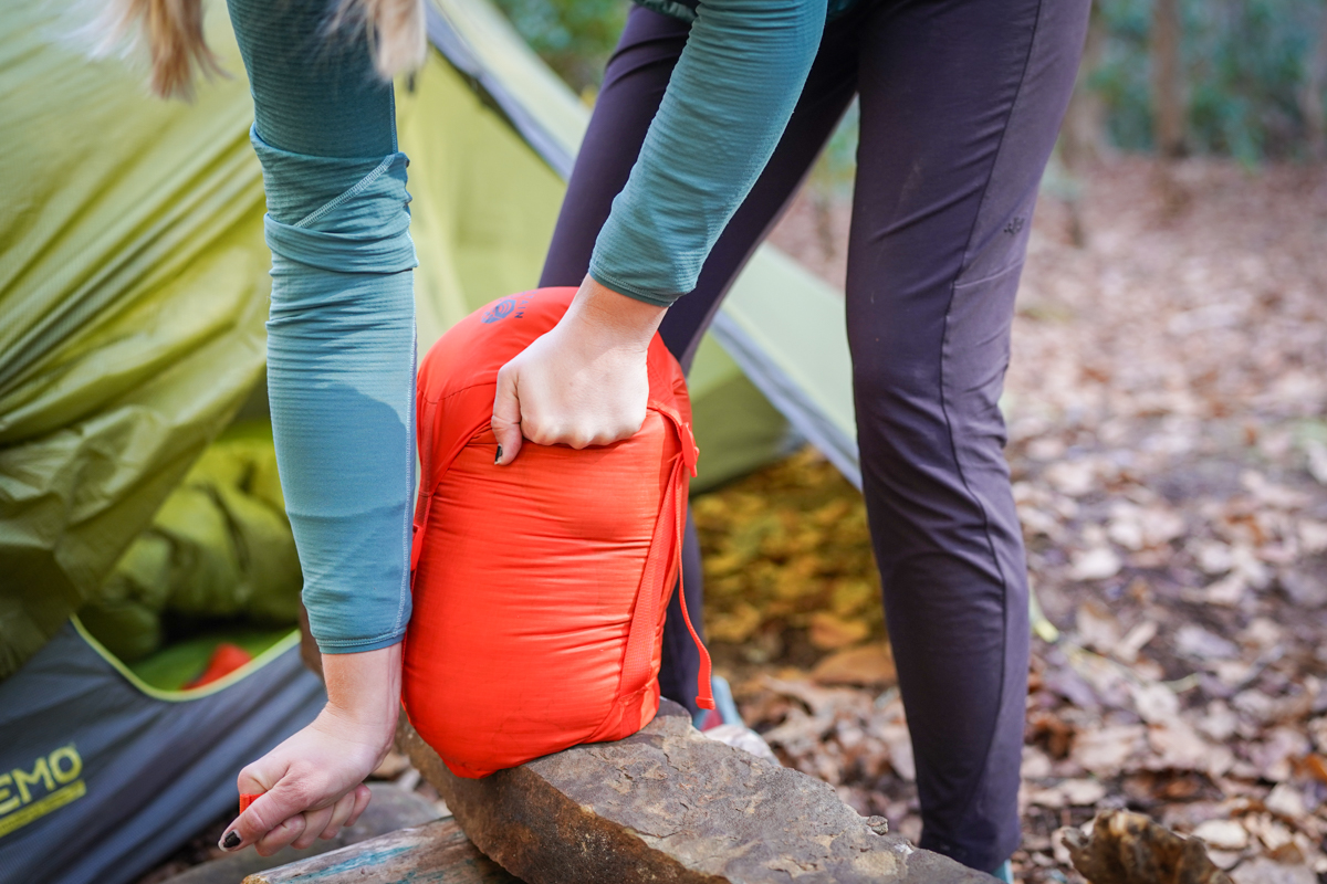 A camper uses the cinch straps on her stuff sack to really reduce the size of her bag.