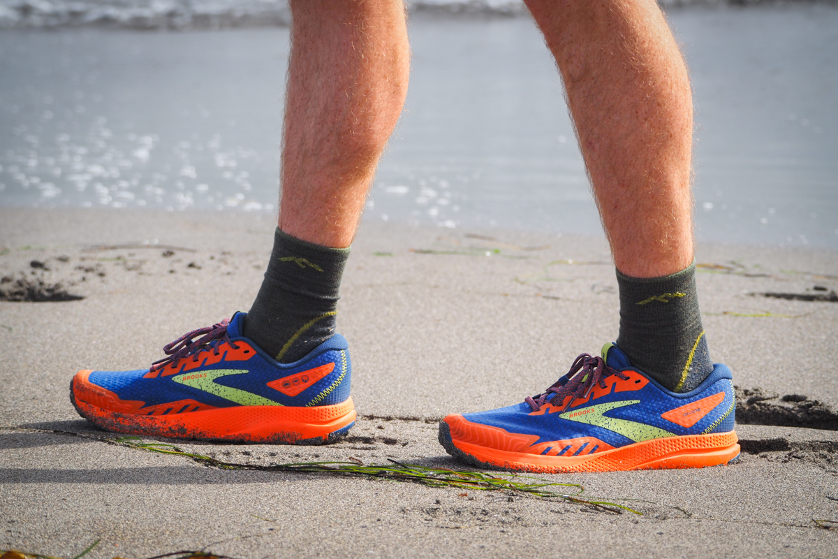 A runner wearing Brooks Divide walks along a beachfront.