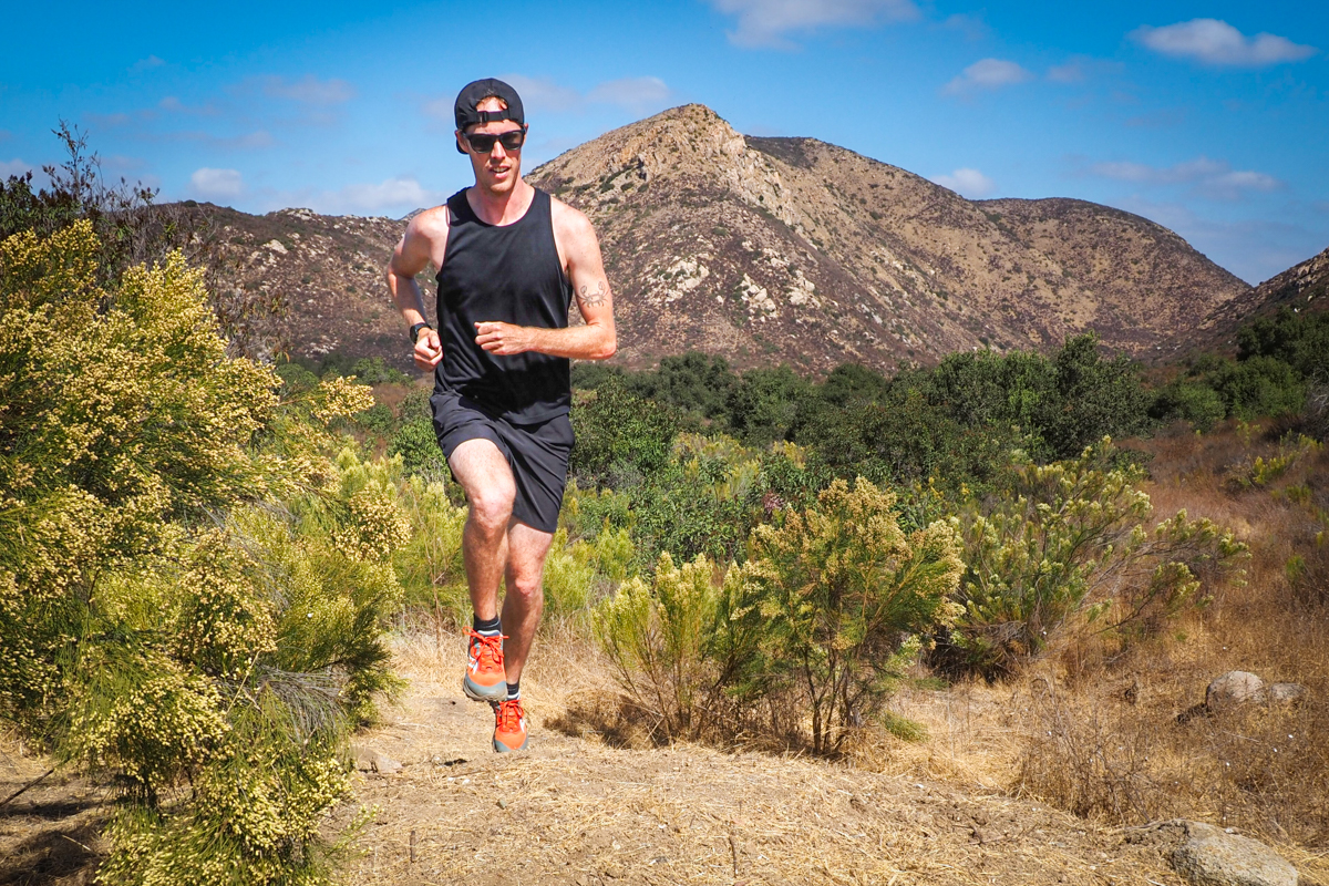 A man runs towards the camera on a dirt trail in the desert wearing the Saucony Peregrine 15 shoes 