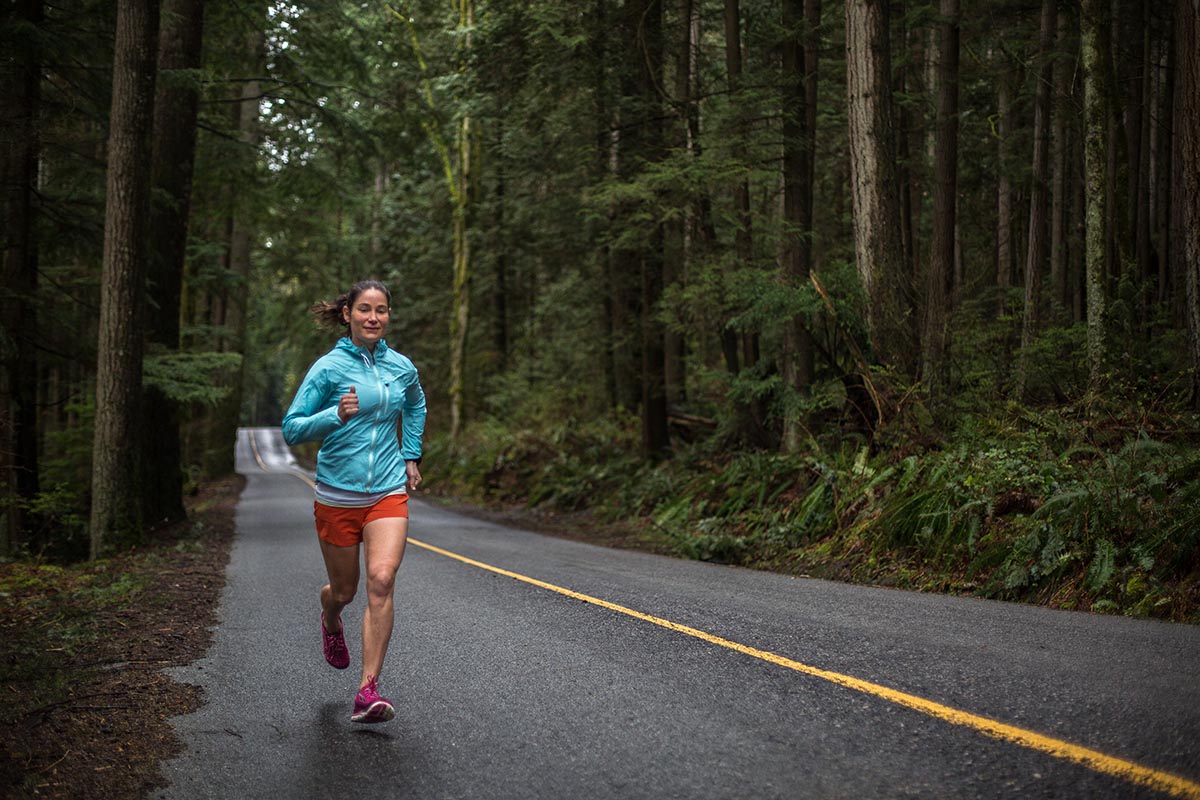 A woman is road running near forest in an Altra zero-drop running shoe