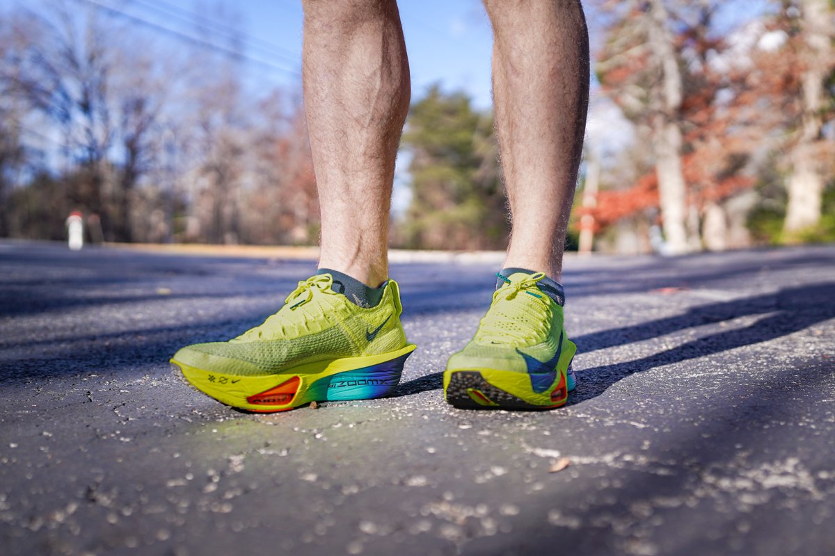 A close-up shot of the Nike AlphaFly 3 running shoes worn by a man and his legs are hairy