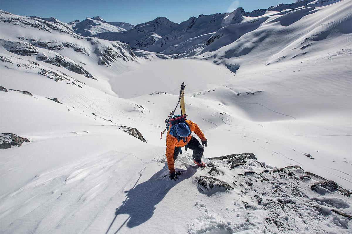 A skier with his skis A-framed on a backpack boot packs up rocky terrain