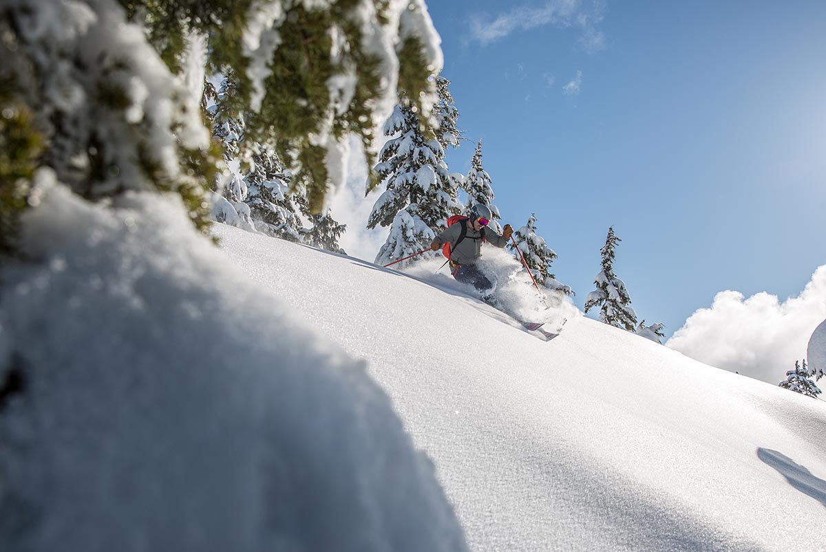 A skier coming down a hill and turning in powder