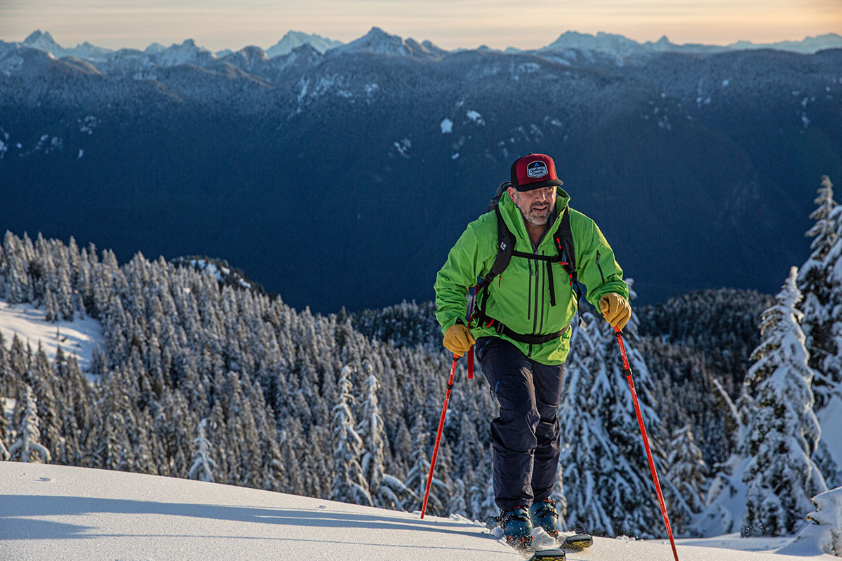 A man in a bright green jacket skinning uphill in the Lange XT3 boot