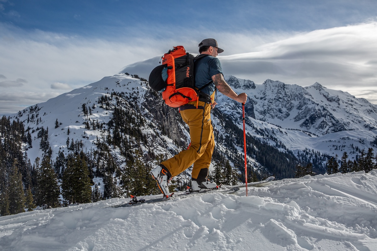 A man in a t-shirt ski tours up a snowy hill