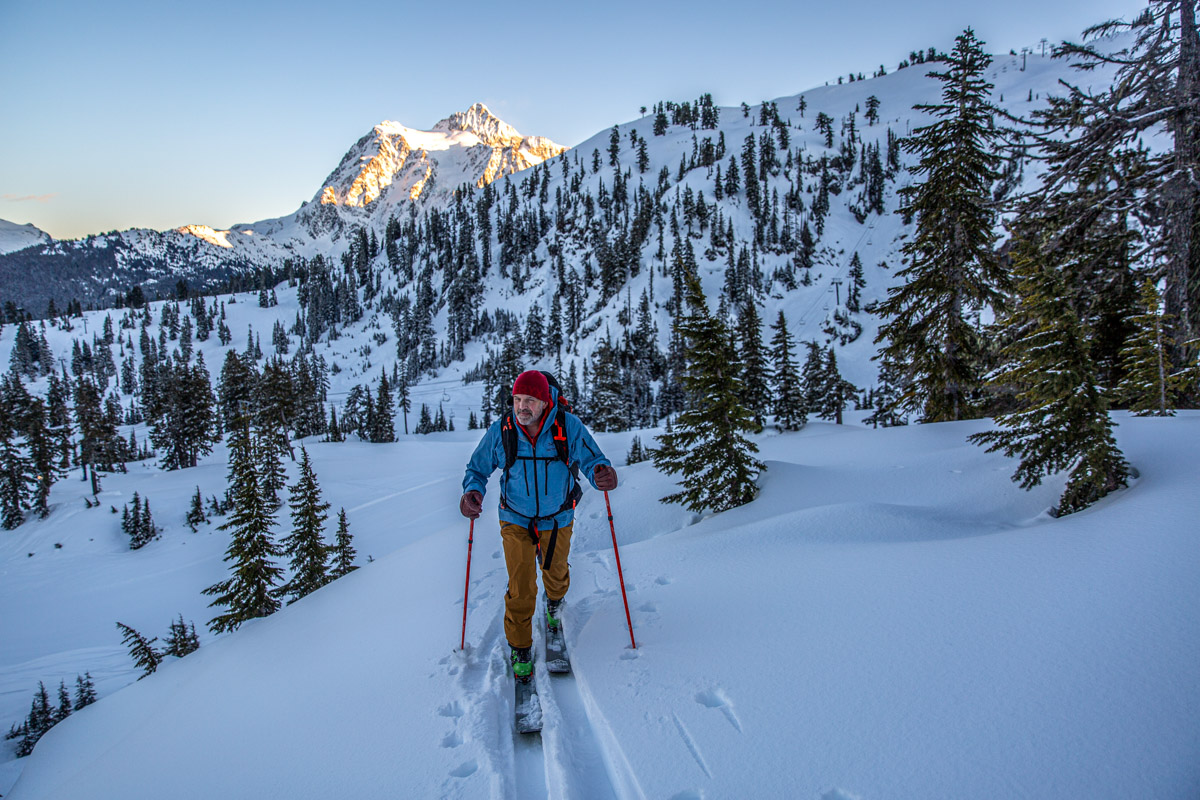A man skiing up a snowy forested hill