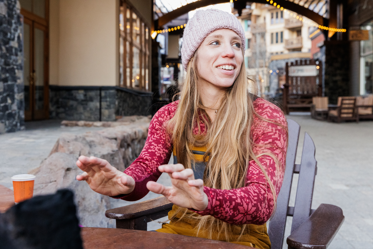 A women sitting by a fire in the Kari Traa Rose Half Zip