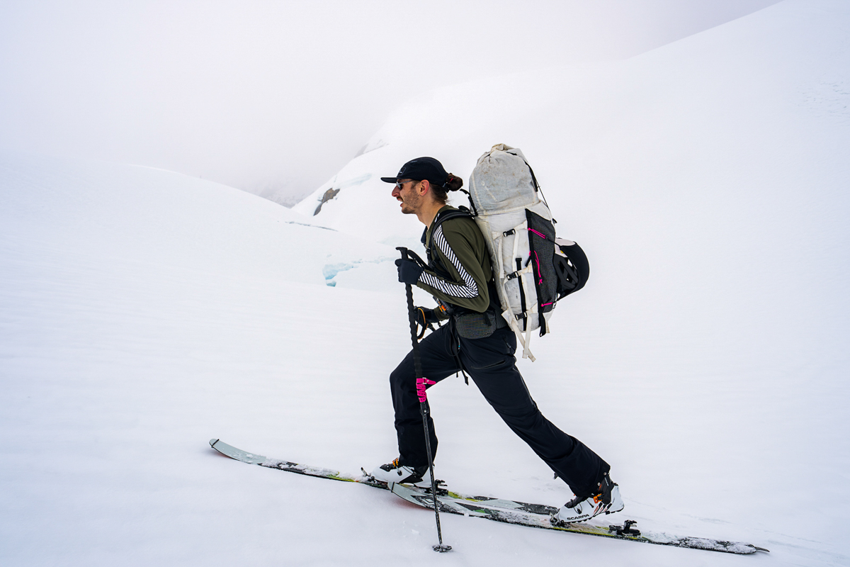 A man skinning uphill on skis in the Helly Hansen Lifa Stripe