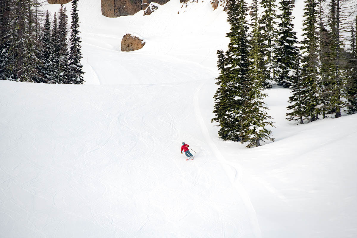 A skier seen from far away coming down a wide and open slope