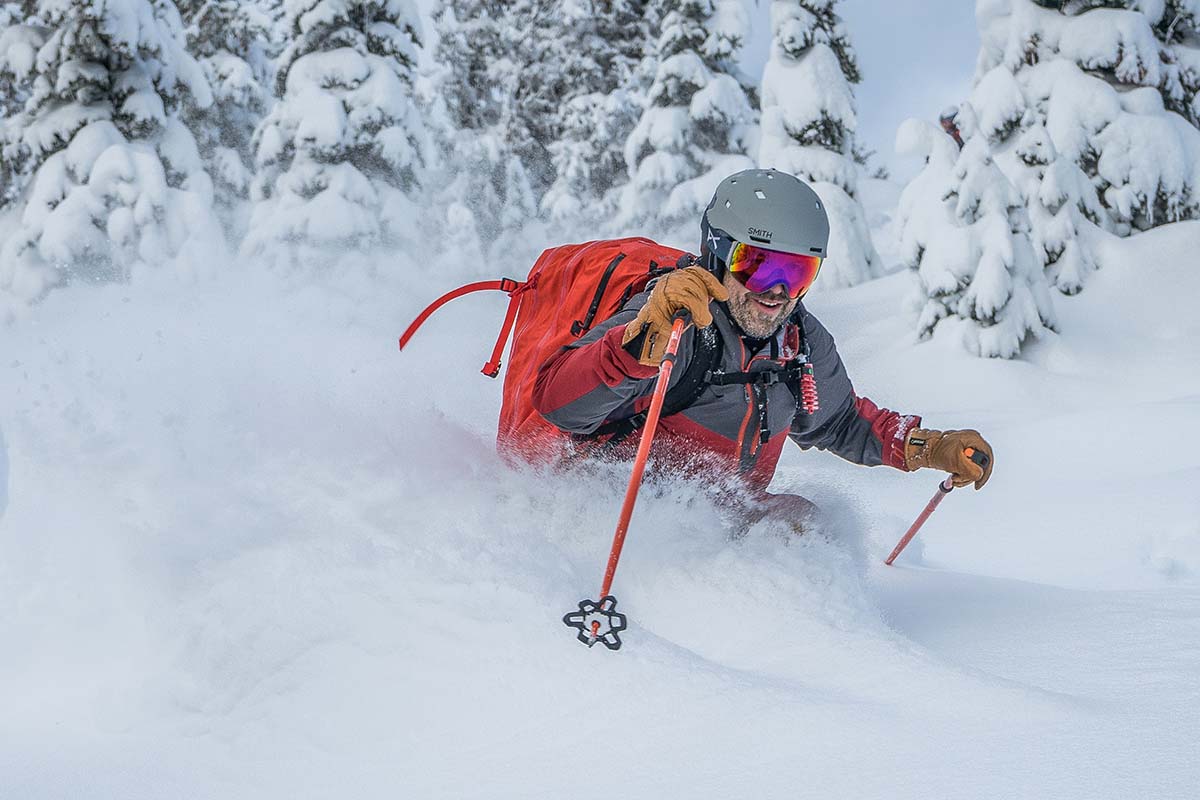 A man is waist deep in powdery snow as he skis down a mountain.