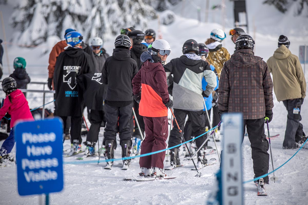 A group of skiers wait to get board a ski lift.