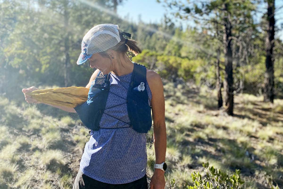 A woman pulls the Mountain Hardwear Ghost Whisperer UL jacket out of a running vest
