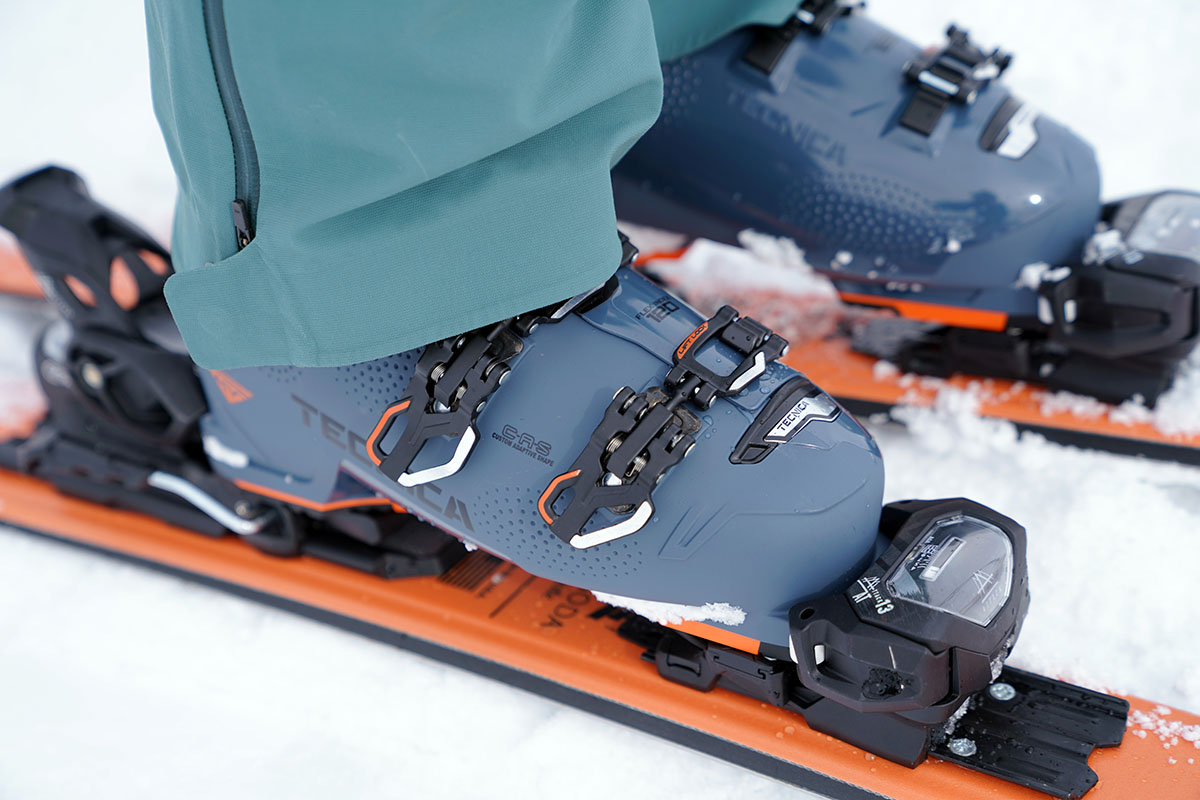 A ski boot is firmly clipped into ski bindings at the toe and heel.