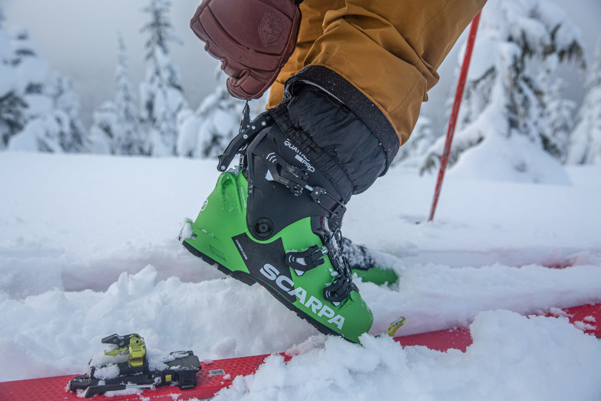 Pulling the lever on the back of a green pair of ski boots